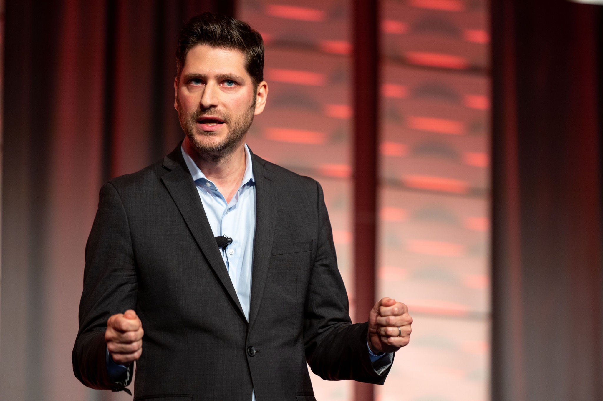 Jaksa Pejnovic en el escenario con chaqueta de traje negra hablando